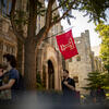The cherry Temple T flag waving above Polett Walk on Main Campus